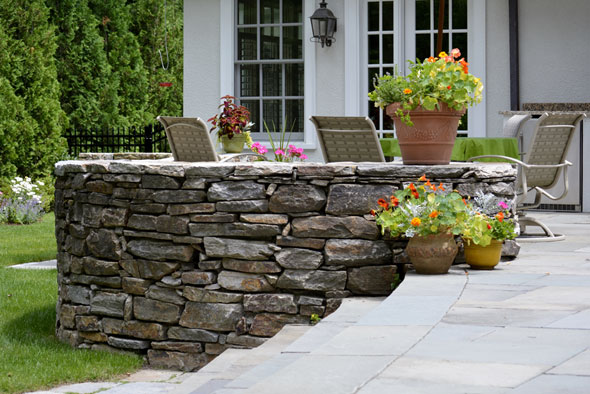 Stone wall with stone patio and potted flowers